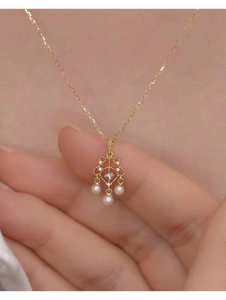 Vue macro d'un pendentif doré vintage ajouré avec diamants et perles suspendues