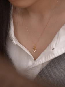 Détail d'un collier vintage en perles dorées avec pendentif ajouré porté par un mannequin