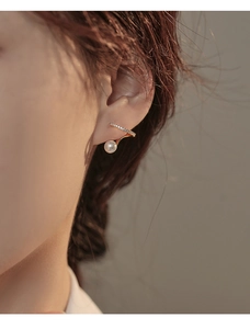 Détail d'un élégant clip d'oreille doré avec diamants pavés et perle blanche ronde