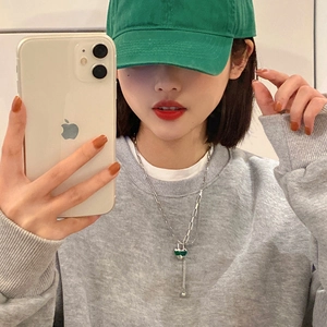 Collier argenté à deux couches avec pendentif cœur vert et glands sur un mannequin