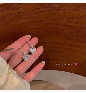 Detailed close-up of sparkling heart-shaped drop earrings featuring white cubic zirconia stones