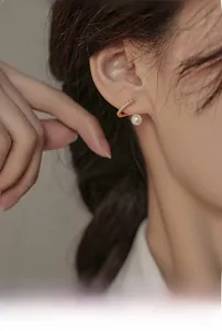 Vue macro d'un earcuff doré orné de zircons scintillants et d'une perle blanche