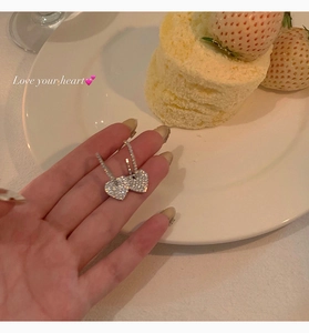 Detailed view of shimmering silver heart drop earrings with pavé set crystals