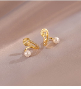 Détail des boucles d'oreilles clips perle avec spirale dorée et accents de zircon brillant