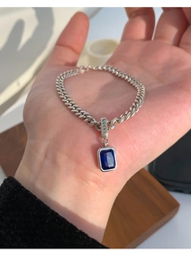 Detail of blue zircon square pendant on silver curb chain with Lucky engraving