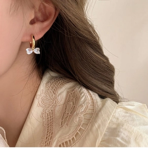 Nahaufnahme eines Zirkon-Bogenohrrings am Modell mit elegantem Goldfinish und Kristallen