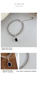 Macro shot of blue zircon pendant and Lucky engraving on heavy link chain bracelet