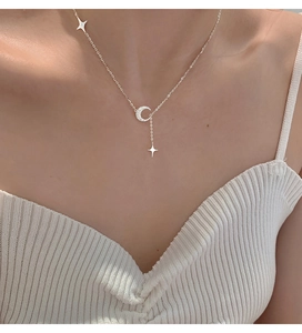 Dettaglio della collana con ciondoli a stella e luna indossata sul collo
