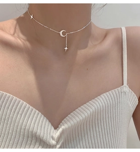 Primo piano della collana con ciondolo a luna e stella satinata sulla clavicola femminile
