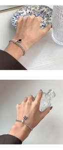 Detail of silver chain bracelet featuring a blue zircon stone and Lucky engraved tag