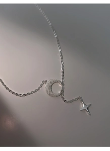 Dettaglio del ciondolo a luna e stella in argento con zirconi su una catena fine