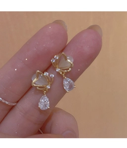 Close-up of golden butterfly earrings with cat's eye stone and teardrop zircon drop