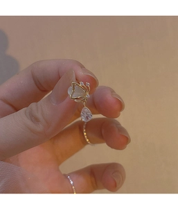 Detailed shot of gold butterfly earrings with opal wings and teardrop zircon pendants