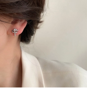 Close-up of silver knot stud earrings with pave set zircons worn on earlobe