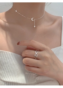 Dettaglio della collana con ciondoli luna e stelle su modella con anello in argento