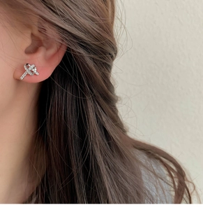 Macro shot of a minimalist X-shaped zircon earring with micro-pave setting on ear