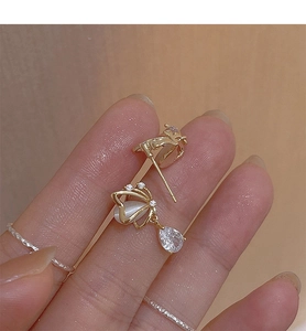 Macro detail of golden butterfly earring with opal stone and clear zircon drop pendant