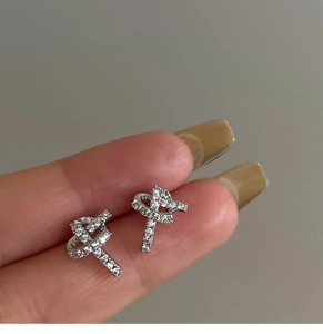 Close-up of silver knot earrings with micro-paved cubic zirconia and elegant design