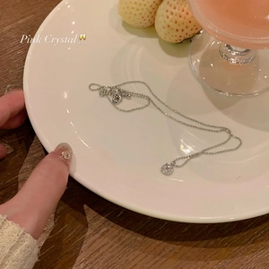 Détail d'un collier à billes argenté avec pendentif en zircon rose posé sur une table