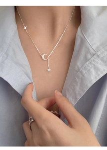 Collana delicata in argento con luna e stelle su modella con camicia a righe azzurre