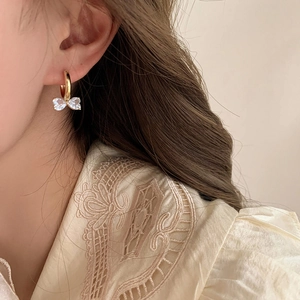 Elegante goldene Schleifenohrringe mit Zirkonia-Anhängern, von einem Model getragen
