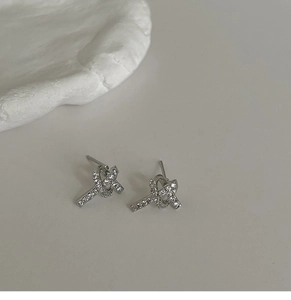 Detail of elegant silver knot earrings with pavé cubic zirconia on a minimalist background