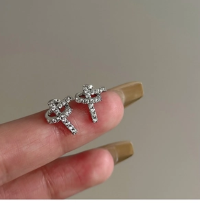 Close-up of silver knot stud earrings with cubic zirconia stones held in hand