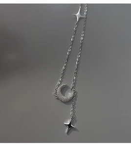 Dettaglio della collana argentata con ciondolo a luna e stelle in zirconi
