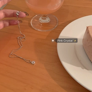 Pendentif en zircon rose sur chaîne à billes fine sur une surface en bois chaud