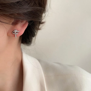 Exquisite silver bow earrings with sparkling cubic zirconia on female model's ear