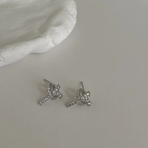 Elegant silver knot earrings with micro-paved zircons on a minimalist artistic background