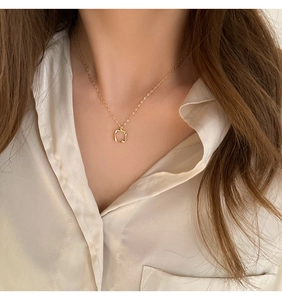 Detailed view of an irregular hollow square gold pendant necklace worn by a model