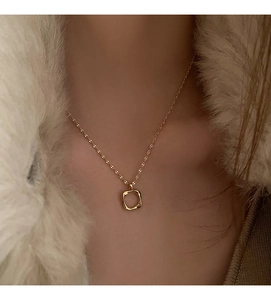 Close-up of a minimalist hollow square pendant necklace worn by a model in winter attire