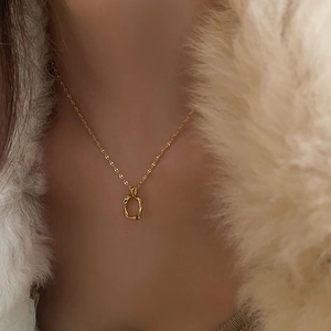 Close-up of a minimalist gold hollow oval pendant necklace worn with a white faux fur coat