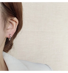 Boucle d'oreille créole argentée en forme de cœur évidé sur un mannequin au style minimaliste