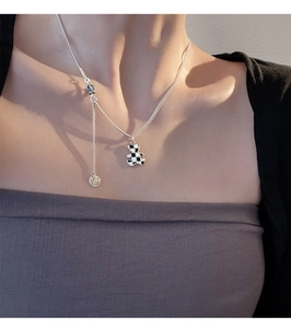 Detail of checkered bear pendant necklace with crown charm on silver chain for women