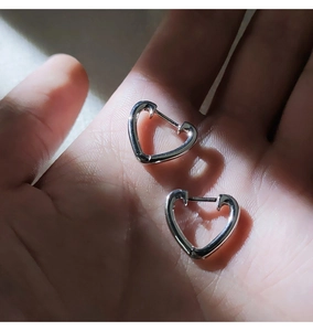 Gros plan de boucles d'oreilles élégantes en forme de cœur argenté montrant taille et détails