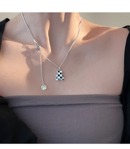 Detail of silver bear pendant with black and white checkerboard pattern and engraved tag