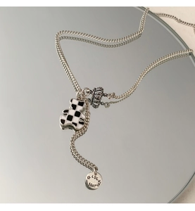 Detail of silver bear pendant necklace with checkered pattern and lucky star charm