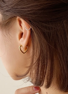 Gros plan d'un modèle portant une boucle d'oreille cœur et un earcuff argenté minimaliste