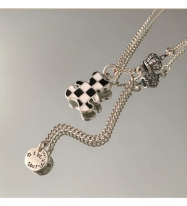 Detailed macro view of S925 silver necklace with checkered bear and crown charms