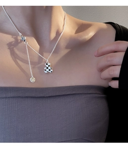 Close-up of bear pendant necklace with black and white checkerboard pattern on the collarbone