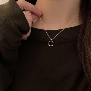 Close-up of a minimalist hollow square pendant necklace in gold finish on a model