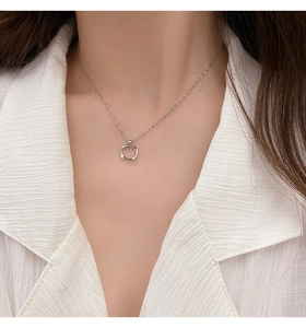 Close-up of minimalist silver hollow square pendant necklace worn on a white textured shirt