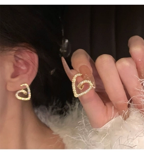 Vue détaillée de boucles d'oreilles cœur en spirale dorée avec zircons brillants