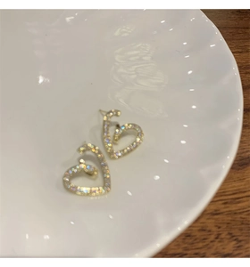 Gros plan de boucles d'oreilles cœur scintillantes avec zircon sur une plaque en céramique