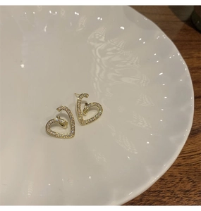 Détail de boucles d'oreilles cœur évidé avec zircons brillants sur une assiette blanche