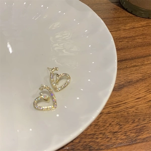 Vue détaillée de boucles d'oreilles cœur évidé avec cristaux brillants sur plat blanc