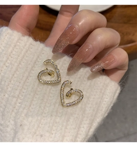 Vue détaillée de boucles d'oreilles cœur en zircon sur fond de tissu tricoté blanc