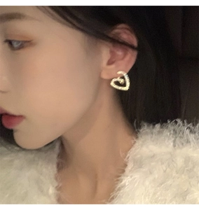 Gros plan de boucles d'oreilles cœur dorées avec texture spirale sur un mannequin